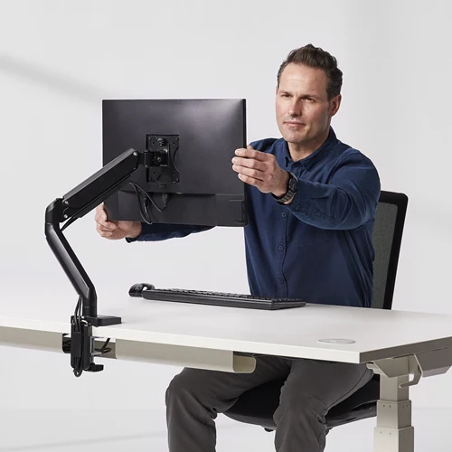 Person adjusting a monitor on the Fellowes Platinum Series single monitor arm